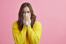 Beautiful Girl Feeling Sick From The Corona Virus Covid-19 And Is Using A Tissue While Standing On A Nice Contrast Background