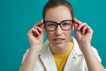 Wall Mural - Beautiful young woman is looking into the camera / mirror to check her new glasses