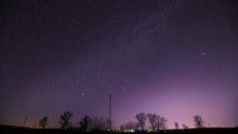 Real Night Sky Stars Above Landscape With Telecommunications Cell Phone Tower Or With Antenna. Natural Starry Sky With Milky Way Galaxy Above Rural Countryside Landscape In Belarus