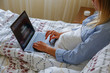 Close up shot of young blonde woman working remotely at home due to coronavirus quarantine concept. Beautiful female sitting in bed with laptop. Background, copy space.