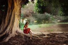 Child Writes In Notebook Under Large Green Tree