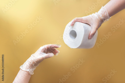 creation of Adam like hands holding toilet paper wearing latex gloves on beige background