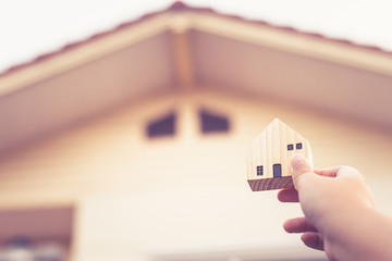 Wall Mural - Hand holding House wooden model house blur background,property and real estate business concept