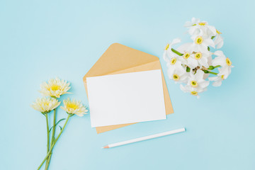 Wall Mural - mockup white wedding invitation and envelope with flowers in a vase on a blue background