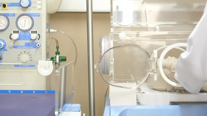 a pediatrician putting an oxygen mask on a newborn infant under an incubator unit (manekin model).