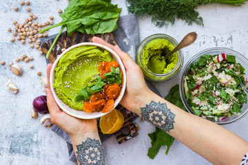 Green spinach chickpea hummus with vegetables. Vegan, vegetarian healthy food in woman hands