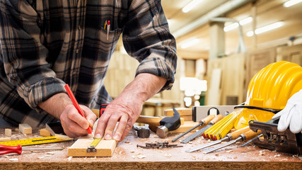 Close-up. Carpenter with pencil and the meter marks the measurement on a wooden board. Construction industry, carpentry workshop.