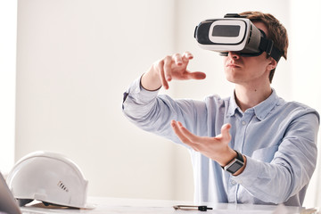 Aufkleber - Busy young architect sitting at desk and gesturing hands while creating floor plan using virtual reality goggles
