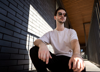 Wall Mural - fashion guy posing in sunglasses against a black urban background