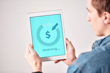 Aufkleber - Over shoulder view of young man receiving money online using banking app on tablet