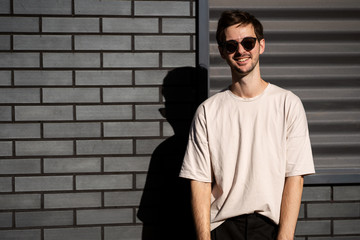 Wall Mural - fashion guy posing in sunglasses against a black urban background