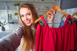 © artiemedvedev - Fashion blogger woman in jeans and turtleneck showing casual colorful shirts on camera. Stylist influencer girl showing trendy clothes filming vlog episode for her channel. Opinion leader sets trends.