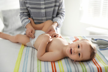 Wall Mural - Mother changing baby's diaper on table at home