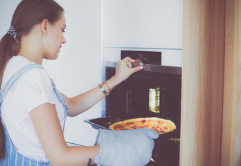 Happy young woman cooking pizza at home