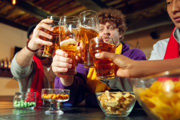 Wall Mural - Sport fans cheering at bar, pub and drinking beer while championship, competition is going. Multiethnic group of friends excited watching translation. Human emotions, expression, supporting concept.