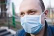 Closeup portrait of sad young man in surgical mask on the street. Pandemic coronavirus 2020. Quarantine.Virus concept. Epidemic infection.