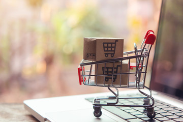 Shopping online concept - Parcel or Paper cartons with a shopping cart logo in a trolley on a laptop keyboard. Shopping service on The online web. offers home delivery..