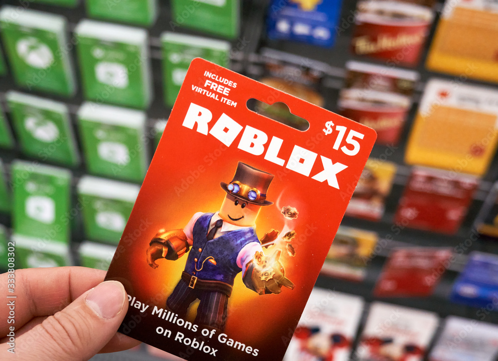 Roblox gift card in a hand over gift cards background.
