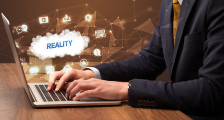 businessman working on laptop with reality inscription, modern technology concept