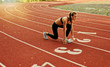 © splitov27 - Young runner woman in sportwear getting ready to run sprint at low start on stadium track with red coated