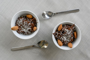 Two chocolate mousses made from banana and avocado. No sugar, only natural ingredients, dates. Healthy diet. Vegan. Mousse is sprinkled with coconut and garnished with almonds. Top view. Copy space.