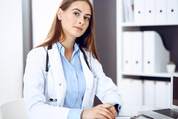 Doctor woman filling up medical form while sitting at the desk in hospital office. Physician at work. Medicine and health care concept