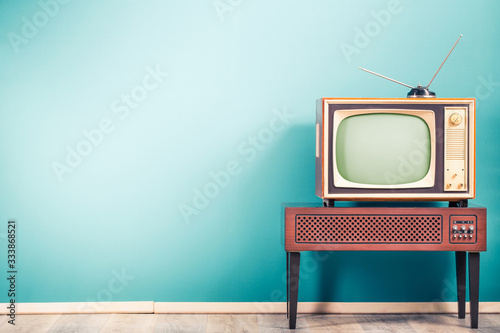 Retro old outdated classic television receiver with TV antenna from circa 60s of XX century on wooden stand with amplifier front gradient mint blue wall background. Vintage style filtered photo © BrAt82