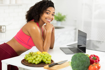 Wall Mural - Black girl using laptop searching recipes looking at camera