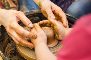 A close up view on ceramic production process on potter's wheel with children. Clay crafts with kids concept.