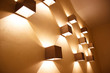Golden brown bronze color cube shaped sconces on a wall. Geometry in design concept