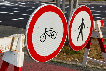 Close up of traffic signs on road barrier prohibiting people and bicycles going forward on empty road