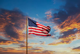 Fototapeta Miasta - An American flag against a blue sky on an old rusty flagpole