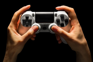 Poster - Hyman hands holding white video game gamepad isolated on a black background