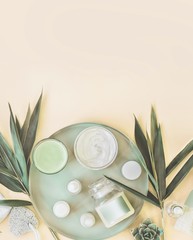 Wall Mural - Various Moisturizing cosmetic products: cream , serum, ampule, mask on light background with palm leaves. Natural herbal facial skin care. Modern. Top view. Copy space. Branding mock-up