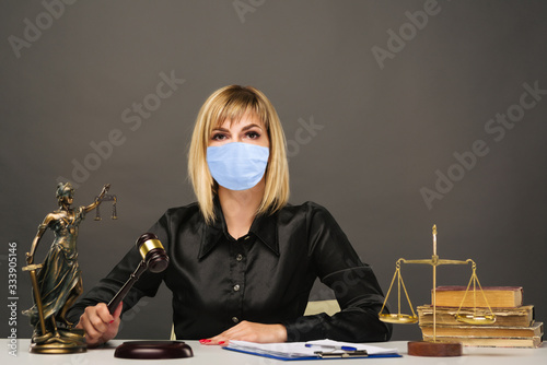 Fotomural A young fair woman judge in protective mask works in her office.
