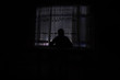 © zef art - Silhouette of a man standing at a window inside the room. Fantasy picture with old vintage lantern at the window inside dark room.