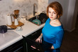 © Aliaksandra - home Office. Quarantine. Girl with red hair in a blue dress with a laptop