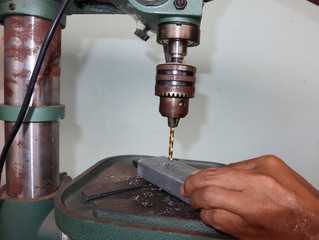 Close up shot  of young man using industrial drill to work with steel. 