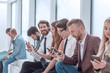 © ASDF - group of diverse young people sitting in the office lobby