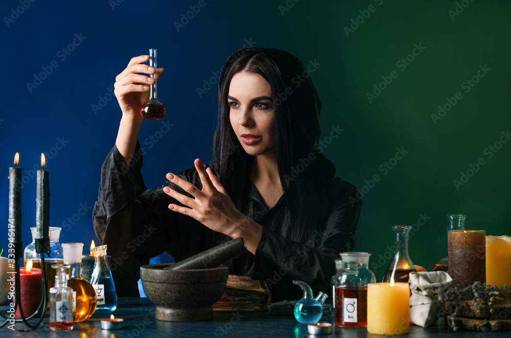 Female alchemist making potion on dark background