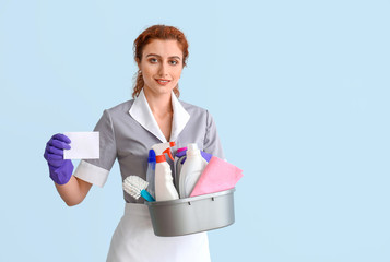 Wall Mural - Beautiful young chambermaid with business card and cleaning supplies on color background