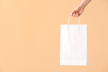 Female Hand With Paper Shopping Bag On Color Background