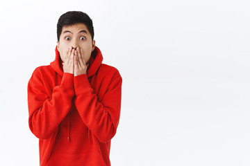 Wall Mural - Waist-up portrait of shocked speechless asian man, gasping, cover mouth and stare camera, express shook with eyes, gossipping, heard exciting incredible news, cant believe, white background