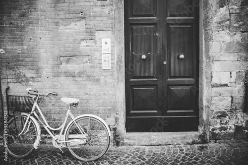 Dekoracja na wymiar  ujecie-w-odcieniach-szarosci-przedstawiajace-stary-rower-oparty-o-betonowa-sciane-obok-drewnianych-drzwi