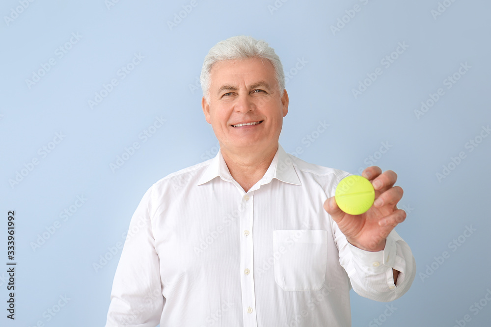 Senior man with pills box on color background