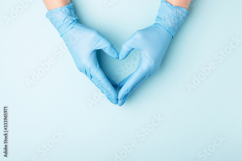 Photographie Doctor's hands in medical gloves in shape of heart on blue background with copy space