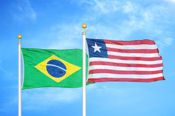 Brazil and Liberia two flags on flagpoles and blue cloudy sky