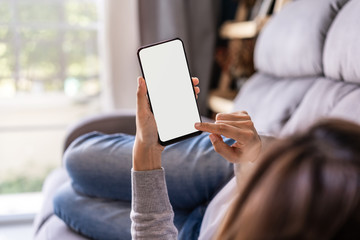 young woman lying on sofa at living room and using cell phone at home