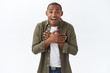 © Cookie Studio - Portrait of happy surprised african-american man look with disbelief and amazement at camera, bending look closer, hold hands on heart grateful, appreciate cute unexpected gift, white background