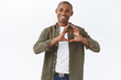 © Cookie Studio - Portrait of happy handsome romantic man in casual clothes, sharing his love and happiness with family, show heart gesture and smiling sincere, confess sympathy, standing white background